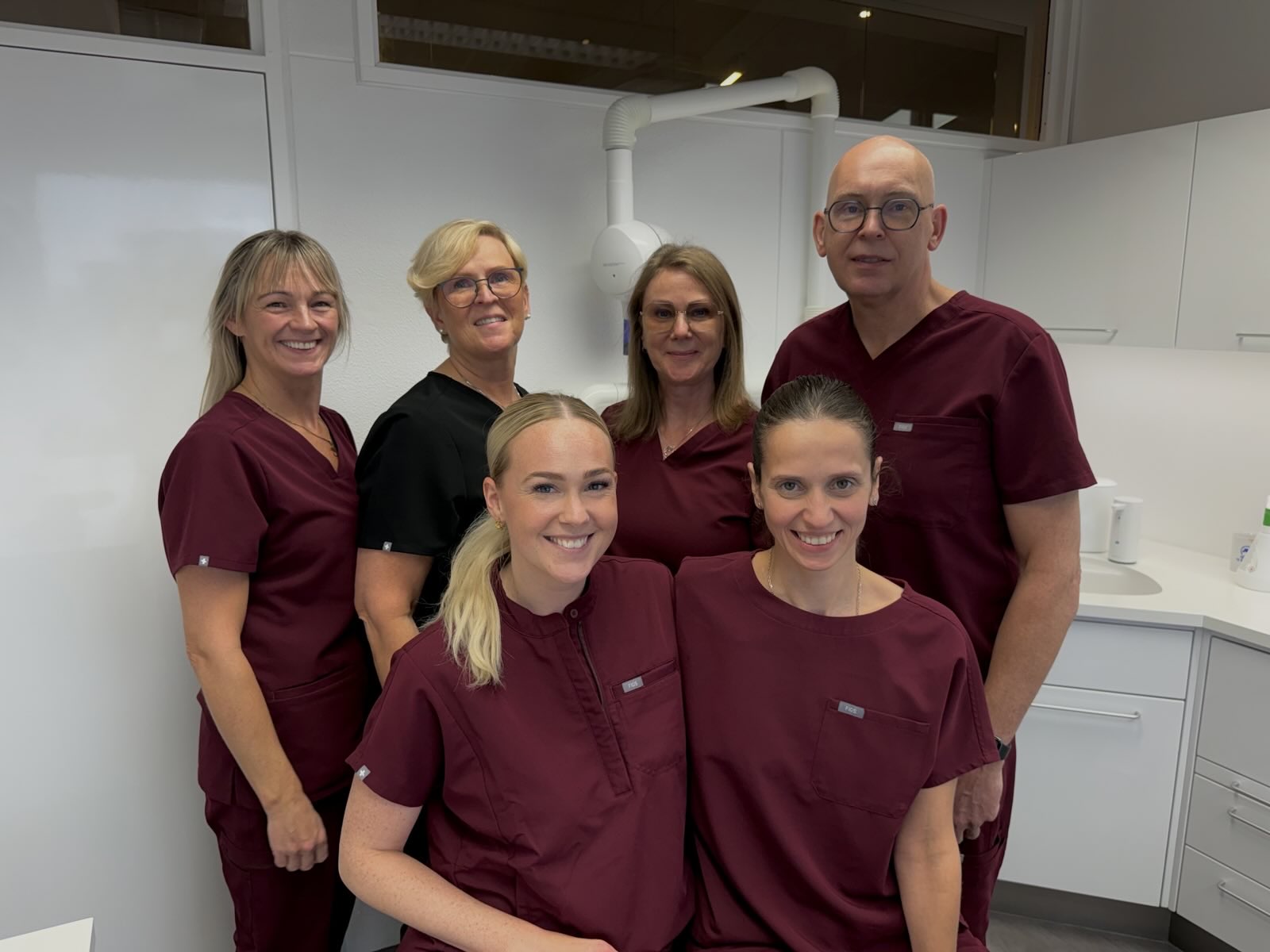 Faglegt teymi tannlæknastofunnar brosandi í nútímalegri stofu
